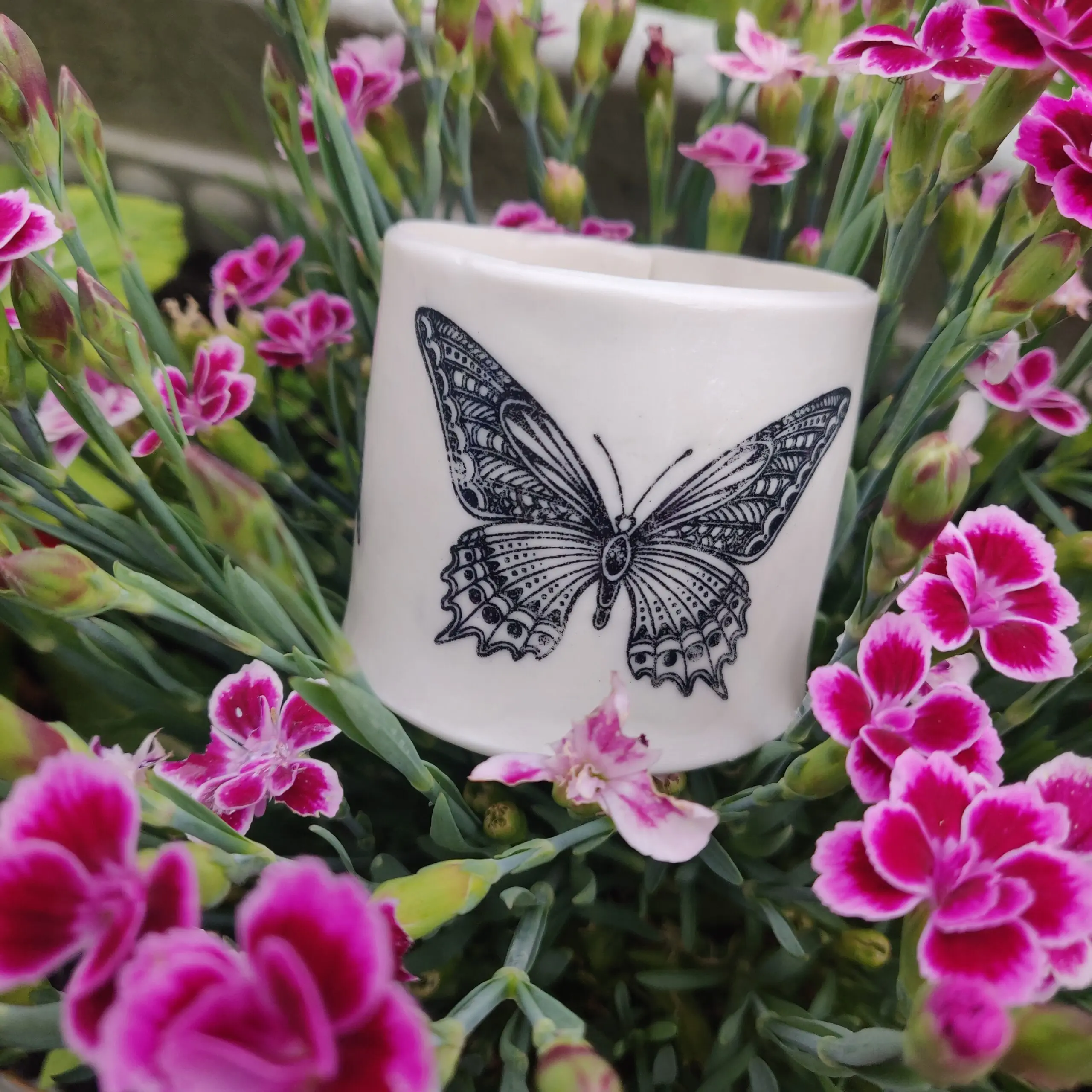 Enchanted Butterfly Porcelain Tealight Holder featuring a black butterfly motif amidst vibrant pink flowers.